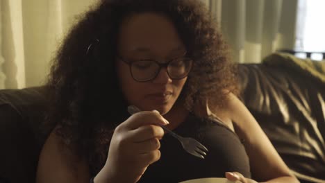 Mujer-Afro-Europea-Rizada-Comiendo-De-Un-Tazón-En-El-Sofá-De-La-Sala