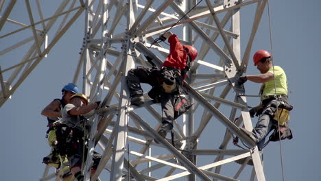 Four-workers-at-height-are-installing-a-high-voltage-pylon