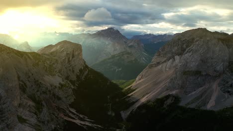 Drone-shot-capturing-the-ethereal-beauty-of-the-Dolomites-bathed-in-morning-light,-with-steep-cliffs-and-verdant-valleys-below