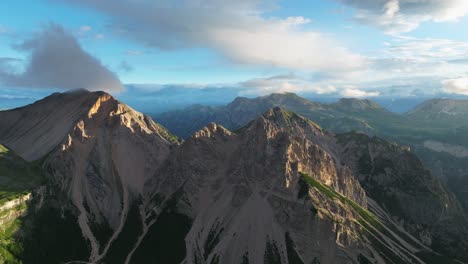 Aerial-drone-footage-of-the-sun-kissed-peaks-of-the-Dolomites-in-San-Vigilio,-captured-shortly-after-sunrise,-revealing-the-grandeur-of-its-rugged-slopes