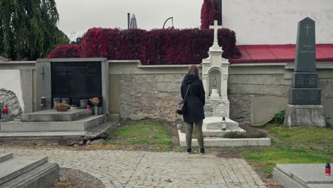 Girl-standing-in-front-of-a-tombstone-while-visiting-a-graveyard