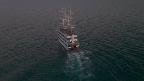 Luftaufnahme-Eines-Mehrstöckigen-Segelschiffs-Mit-Masten,-Die-Eine-Spur-über-Das-Mittelmeer-Bei-Sonnenuntergang-Hinterlassen