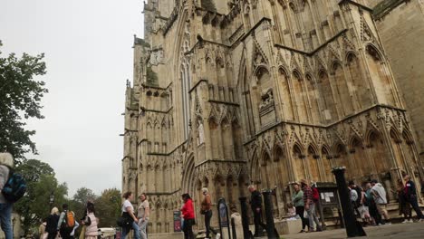 Low-angle-shot-of-tourists-waiting-in-a-queue-outside-of-York-Minster,-England