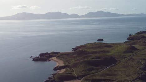 Luftaufnahme,-Die-Bei-Sonnenaufgang-über-Der-Idyllischen-Insel-Ynys-Llanddwyn-Mit-Der-Dunstigen-Snowdonia-Bergkette-über-Dem-Schimmernden-Irischen-Meer-Kreist