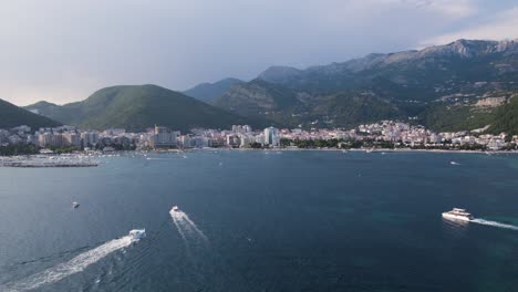 Budva,-Montenegro-coastal-skyline-with-boats-and-mountains-backdrop---Aerial
