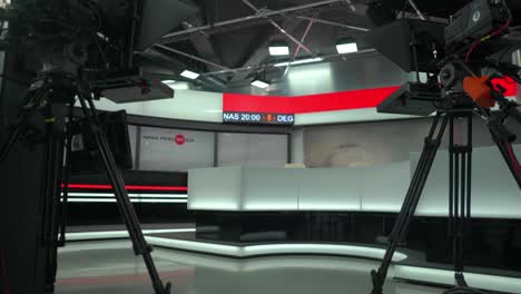 Cameras-with-teleprompter-and-empty-presentation-desk-at-tv-news-broadcast-set