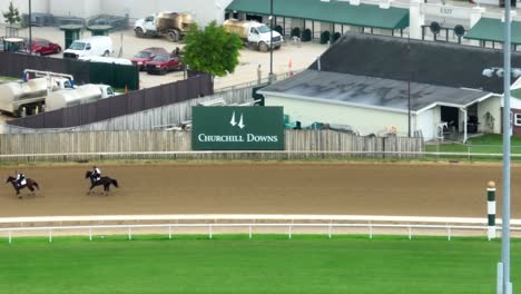 Horses-racing-on-the-track-at-Churchill-Downs-with-vehicles-and-buildings-in-the-background