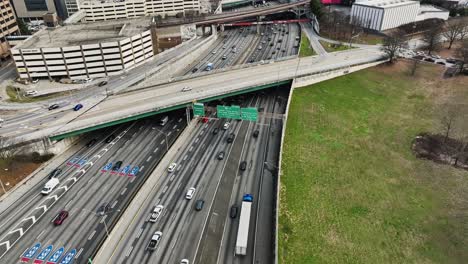 Drone-tilt-up-shot-of-crowded-road-in-Atlanta-City-with-crossing-bridge-in-downtown