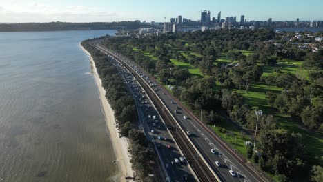 Traffic-along-highway-with-Golf-Club-and-skyscrapers-of-CBD-in-background,-Perth-city-in-Australia