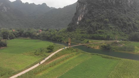 Phong-Nha-with-old-suspension-bridge-over-river-at-Vietnam,-aerial