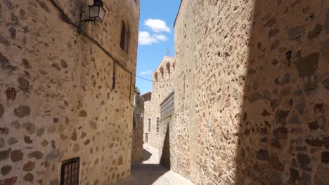 Tilt-down-shot-of-Stone-Walls-in-Empty-Street-in-Caceres-old-Town,-Spain