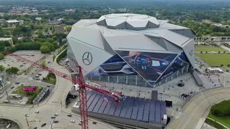 Aerial-top-down-shot-of-crane-with-waving-american-flag-and-mercedes-benz-stadium-in-background