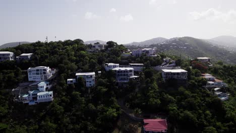 Aerial-drone-wide-zoom-out-shot-revealing-homes-on-the-hill-and-mountains-in-the-background-st