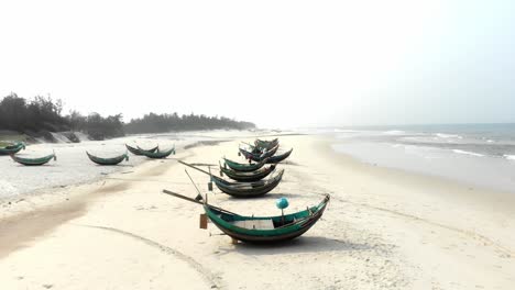 Local-fishing-boats-on-shore-at-Trung-Thanh-Beach-Vietnam,-aerial