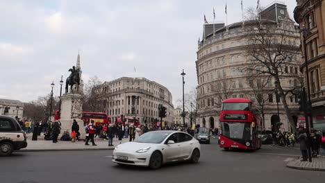 Londoner-Stadtverkehr-Am-Trafalgar-Kreisverkehr-Mit-Schwarzen-Taxis-Und-Roten-Doppeldeckerbussen,-Die-An-Menschen-Protestieren