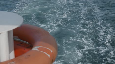 Boat-creates-turbulent-wake-stern-of-vessel-with-orange-life-bouy