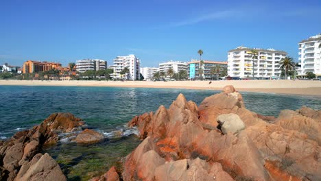 Images-on-rocks-of-a-Mediterranean-beach-with-buildings-in-the-background-Fenals-Lloret-De-Mar
