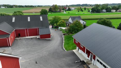 American-farm-with-red-barns,-washline,-farmhouse-and-rural-countryside-with-fields-and-trees