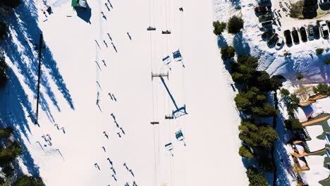 Wintersport,-Belebte-Skipiste-Mit-Leuten,-Die-Mit-Dem-Seillift-Fahren,-Neben-Vollem-Parkplatz-Und-überfüllter-Strecke
