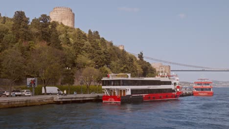 Leuchtend-Rote-Kreuzfahrttouristenboote-Entlang-Der-Malerischen-Bosporusküste