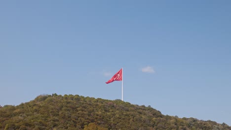 Hilly-wooded-landscape-with-National-red-flag-of-Turkey-raised-above