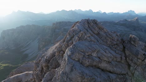 A-close-up-view-of-the-Dolomites-showcases-its-intricate-rock-layers-and-textures,-contrasted-against-a-backdrop-of-distant-peaks-under-a-muted-sky