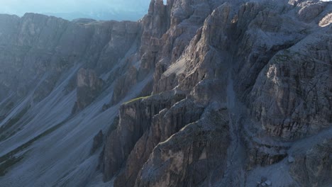 Luftdrohnenaufnahme-Der-Dolomiten-Mit-Schroffen-Felswänden,-Deren-Komplizierte-Texturen-Und-Formationen-Durch-Die-Sonnenstrahlen-Hervorgehoben-Werden