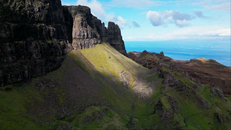 Light-bursts-between-cliffs-in-the-Scottish-highlands-illuminating-grassy-patch-below-exposed-rock