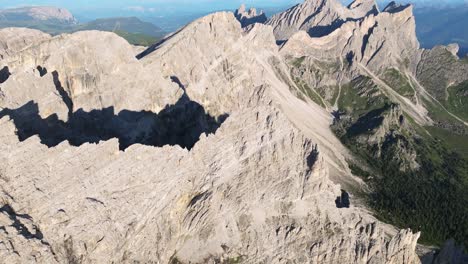 Perspectiva-Aérea-De-Los-Dolomitas,-Que-Revela-La-Vasta-Extensión-De-Formaciones-Rocosas-Irregulares-Yuxtapuestas-A-Exuberantes-Valles-Verdes.