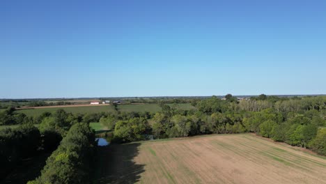 Drone-footage-rising-from-French-field-showing-countryside-and-clear-blue-sky