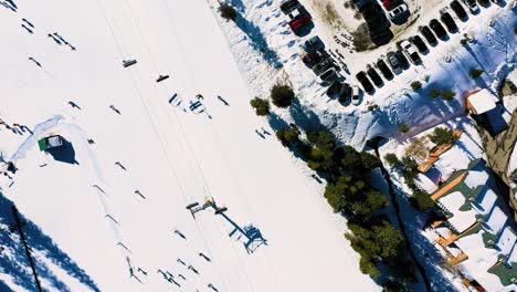 Vista-Aérea-Por-Drones-De-Una-Concurrida-Pista-De-Esquí-Y-Un-Estacionamiento-Completo-Con-Gente-Montando-En-Telesilla-En-Un-Sendero-Lleno-De-Gente