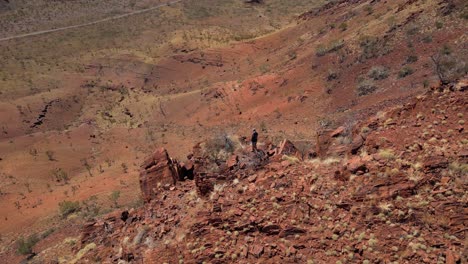 Aerial-orbit-shot-showing-person-standing-on-edge-in-hilly-desert-of-Australia-and-enjoying-nature-view