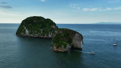 Aerial-view-of-a-boat-driving-through-the-a-Mismalyoa-arches-in-Puerto-Vallarta,-Mexico