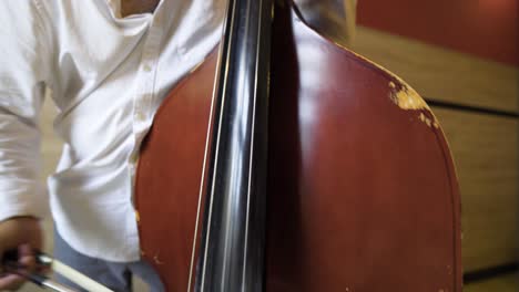 bottom-up-view-of-a-mixed-ethnicity-Roma-Gypsy-male-playing-damaged-weary-antique-instrument-cello-hitting-notes-strings-natural-Romani-talent-hidden-mysterious-culture-close-up-white-shirt-elder-man