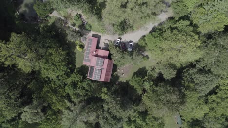 drone-footage-captures-a-picturesque-bird's-eye-view-of-a-charming-red-house-nestled-in-the-heart-of-a-lush-forest