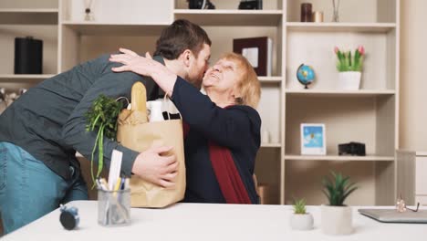 young-man-brings-a-package-of-groceries-to-the-old-woman-with-care-and-embraces-her