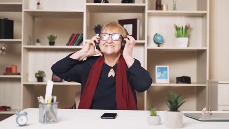 Eine-ältere-Frau-Setzt-Sich-Drahtlose-Kopfhörer-Auf,-Tanzt-Und-Singt-Mit-Und-Hört-Musik-Auf-Ihrem-Smartphone