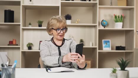 older-woman-takes-a-smartphone-in-her-hands-and-looks-at-something-surprising