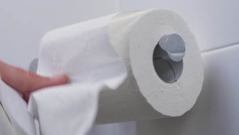 Close-up-slow-motion-shot-of-pulling-toilet-roll-tissue-paper-on-toilet-holder-bathroom-people-personal-hygiene-loo-4K
