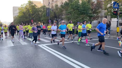 Marathon-runners-in-bright-yellow-green-shirts-race-on-asphalt-in-down-town-at-early-morning