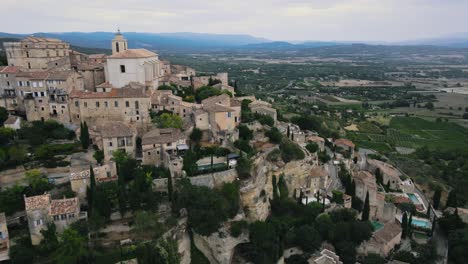 Aerial-backwards-shot-of-historic-french-gordes-villlage-on-hill-during-sunny-day-in-France