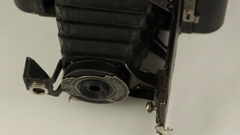 Old-vintage-folding-camera-by-Kodak-with-bellows-out,-rotates-on-white