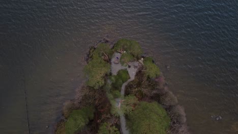 Aerial-drone-shot-looking-down-onto-ripples-in-water-of-lake-and-peninsula,-at-Friar's-Crag-in-Keswick