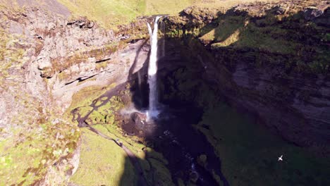 Aerial:-Flyover-reveal-of-Kvernufoss-horsetail-waterfall-and-hidden-alcove-where-you-can-go-behind-the-waterfall