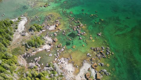 Aerial-view-topdown-pan-of-forested-beach-and-boulder-field-in-lake-huron