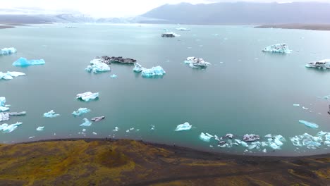 Slow-aerial-revealing-shot-of-icebergs-melting-at-Glaciers-in-Iceland-from-climate-change