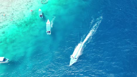 Luftaufnahme-Aus-Der-Vogelperspektive-über-Den-Strand-Von-Gili-Meno,-Eingebettet-Zwischen-Den-Idyllischen-Gili-Inseln-Indonesiens,-Boote-Schwimmen-über-Kristallblauem-Wasser