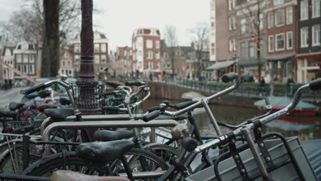 Amsterdam-canal-view-with-bicycles-lined-up,-historic-houses,-and-moored-boats