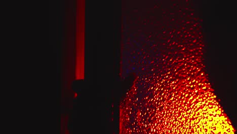 Sinister-scary-silhouette-crawls,-opens-glass-door-under-red-light