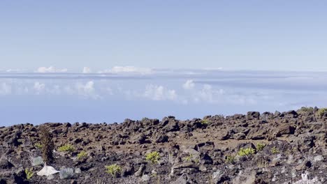 Cinematic-panning-shot-of-the-barren-rocky-landscape-above-the-clouds-at-the-summit-of-Haleakala-in-Maui,-Hawai'i